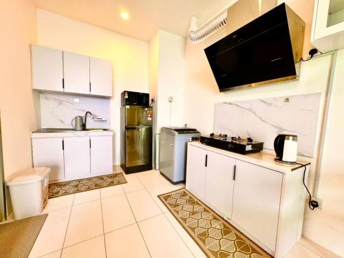 a kitchen with white cabinets and a tv on the wall at TT3 SOHO 2BR HIGH Flr CORNER BALCONY UNIMAS SAMARAHAN in Kuching