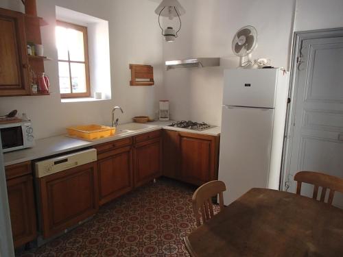 a kitchen with a white refrigerator and a table at Appartement Authentique Montaigut in Montégut