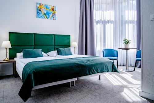 a bedroom with a large green bed and blue chairs at Elisabeth Old Town in Bratislava