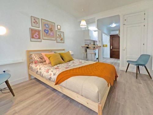 a bedroom with a large bed and a blue chair at Cadizz- Estudio Las Flores in El Puerto de Santa María