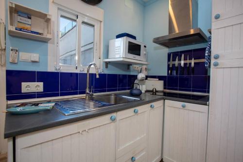 a kitchen with a sink and a microwave at Terraza junto a La Caleta El Faro del Manteca I in Cádiz