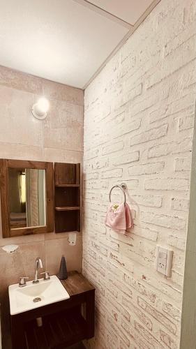 Un baño con lavabo y una pared de ladrillo blanco. en Sol Campestre, en La Adela