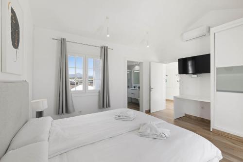 a white bedroom with a large bed and a window at Villa Yaiza Secret 2 in Yaiza