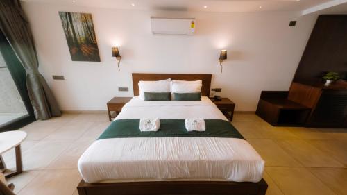 a bedroom with a large bed with two pillows at Vee Resort- The Suites of Royals in Mahabaleshwar