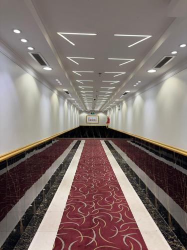an empty corridor with a red carpet in a building at شركة سعادات الانماء-دار الطائف سويتس in Quai