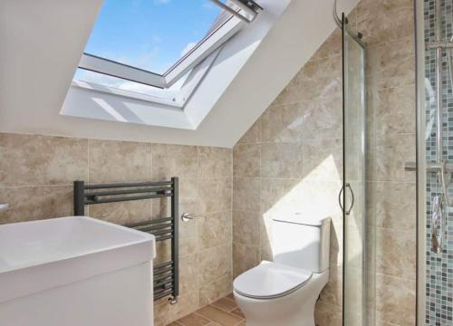 a bathroom with a toilet and a skylight at Stylish 1BR Apartment Wembley Stadium Sleeps 4 in London