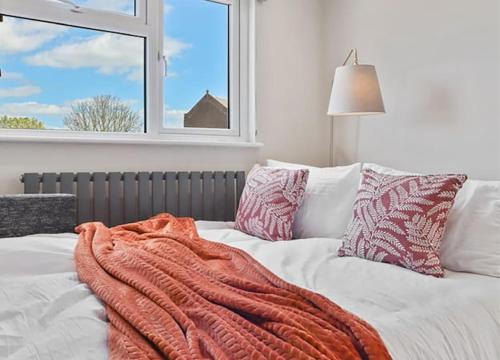 a bed with an orange blanket on it with a window at Stylish 1BR Apartment Wembley Stadium Sleeps 4 in London