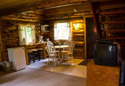 Una sala de estar con una mesa y sillas y un televisor. en Midnight Sun Log Cabins, en Moose Pass