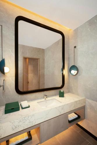 a bathroom with a sink and a large mirror at Iconic Marjorie Hotel, Penang, a Tribute Portfolio Hotel in Bayan Lepas