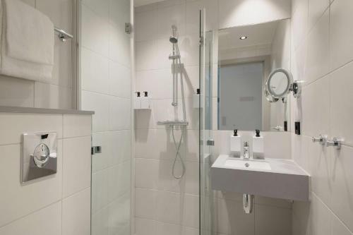 a white bathroom with a sink and a shower at Scandic Torget Bergen in Bergen