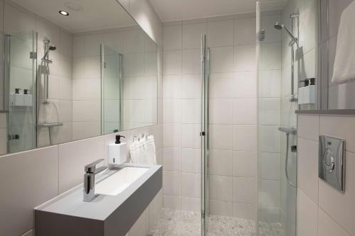 a bathroom with a sink and a glass shower at Scandic Torget Bergen in Bergen