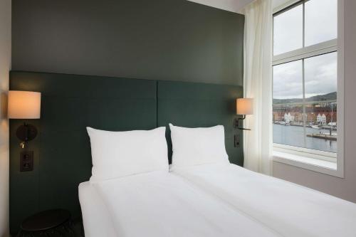 a bedroom with a large white bed with a window at Scandic Torget Bergen in Bergen