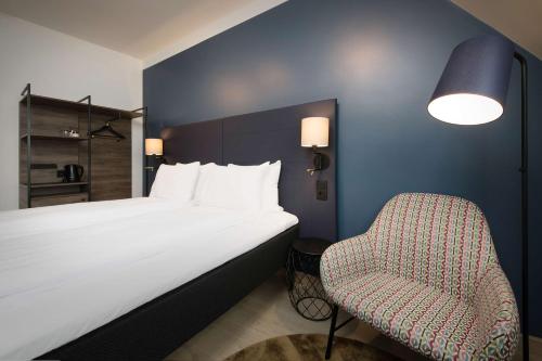 a hotel room with a bed and a chair at Scandic Torget Bergen in Bergen