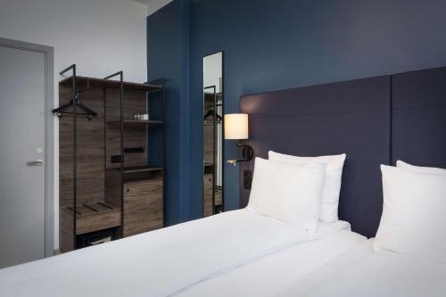 a bedroom with a large white bed and a mirror at Scandic Torget Bergen in Bergen