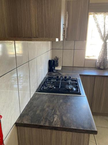 Desert Buddy Accomodations في ويندهوك: مطبخ مع موقد وطاولة عمل