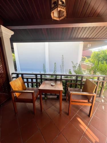 a patio with two chairs and a table on a balcony at QUEEN'S HOUSE in Luang Prabang