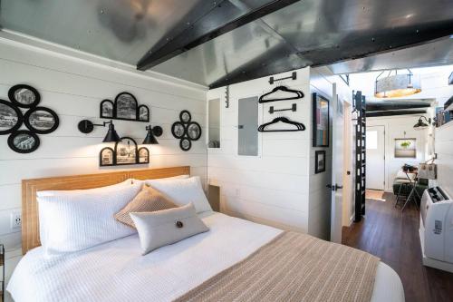 a bedroom with a white bed and some clocks on the wall at Cozy Caboose Retreat | Sleeps 4 | Fire Pit in Fredericktown