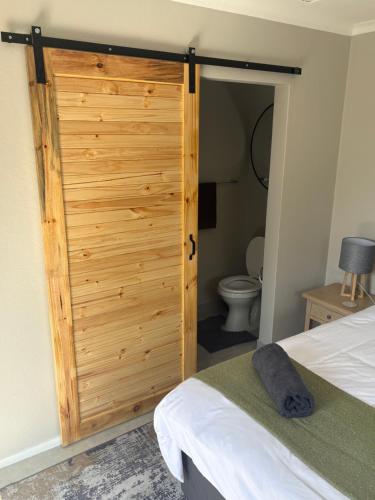a wooden door in a bedroom with a toilet at Serenity Luxury Guesthouse in Krugersdorp