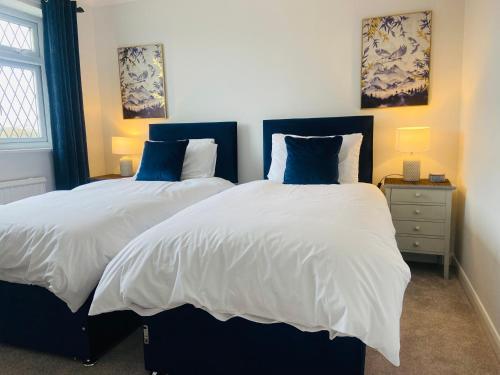 a bedroom with two beds with white and blue pillows at Danby House Messingham nr Brigg, Blyton, Hibaldstow, Scuthorpe- Ideal for Families, Business, Golfers, Wedding Guests in Messingham