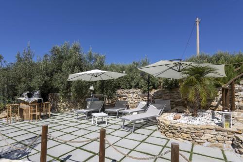 a patio with chairs and umbrellas on a stone patio at Villino Il Melograno in Menfi