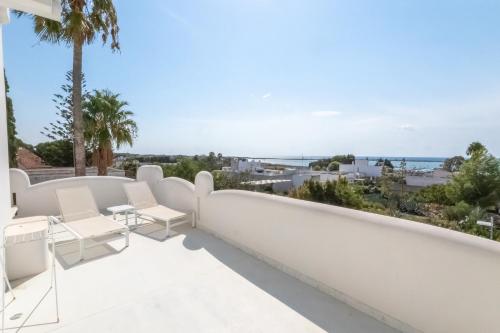 a balcony with white furniture and a view of the ocean at Valentino Luxury Rooms in Porto Cesareo