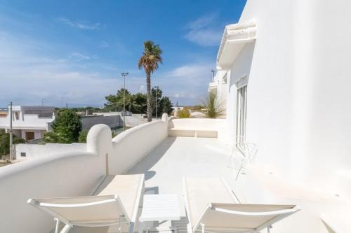 a white house with white chairs and a balcony at Valentino Luxury Rooms in Porto Cesareo