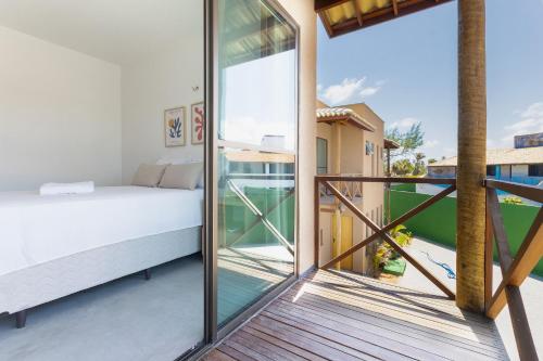 a bedroom with a bed and a balcony with glass doors at Beachfront Duplex #A6 - Aquiráz By Carpediem in Aquiraz