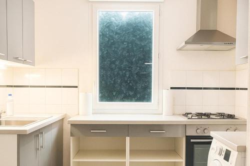 Una cocina blanca con ventana y fregadero. en 2-Bed House Sleeps 6 15 mins to Toulouse, en Fenouillet