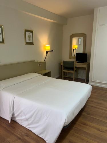 a bedroom with a large white bed and a chair at Hotel Alda Ribeira in Ribeira