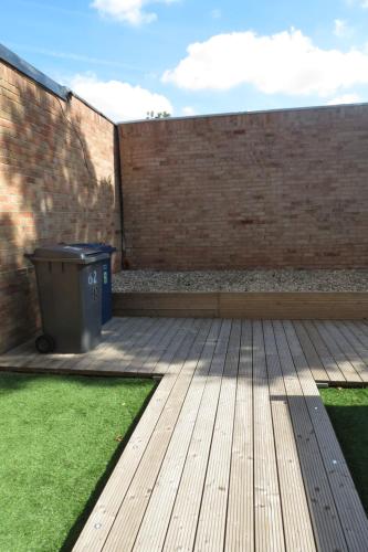 a patio with a trash can next to a brick wall at Comfortable Family Suite For 4 People in Stone Grove
