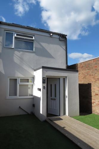a white house with a door and a grass yard at Comfortable Family Suite For 4 People in Stone Grove