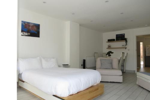 a white bedroom with a bed and a chair at Comfortable Family Suite For 4 People in Stone Grove