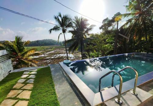 a swimming pool in a yard with palm trees at Ely Field Villa in Galle