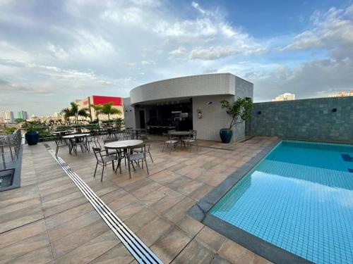 a rooftop patio with a pool and tables and chairs at Studio Unique 2802 com garagem á 15 min do centro de Belém in Belém