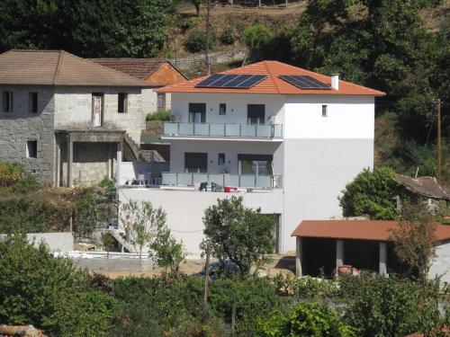 a white house with solar panels on its roof at Manecas House Creative in Reriz