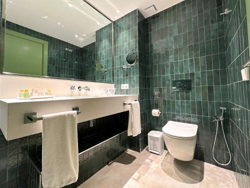 a green tiled bathroom with a toilet and a sink at Ribera de Triana Hotel in Seville