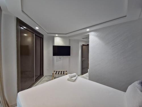 une chambre avec un lit blanc et une télévision dans l'établissement TANGERSUITE FAMILY MARINA BAy, à Tanger