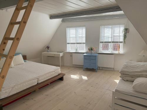 Un dormitorio con una cama tipo escalera y dos ventanas. en Historical Townhouse, en Aabenraa
