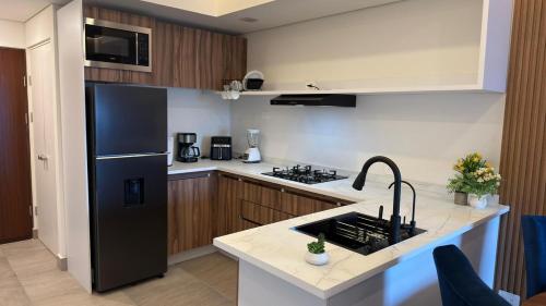 a kitchen with a black refrigerator and a sink at Espectacular y exclusivo departamento en Monterrey in Monterrey