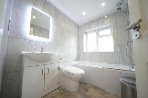 a white bathroom with a sink and a toilet and a window at The Hatton Rooms in New Bedfont