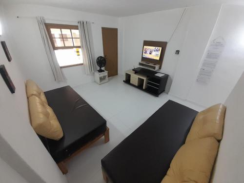 a living room with a couch and a television at Casa com saída p/ praia do Peró Cabo Frio in Peró