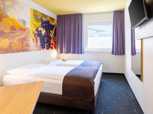 a hotel room with two beds and a tv at B&B Hotel Heilbronn in Heilbronn