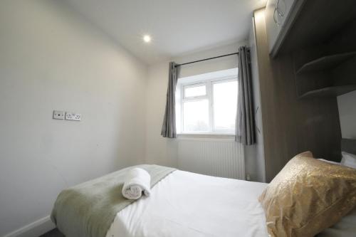 a bedroom with a white bed with a window at The Hatton Rooms in New Bedfont