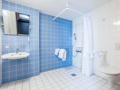a blue tiled bathroom with a toilet and a sink at B&B Hotel Heilbronn in Heilbronn