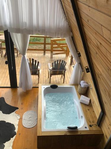 a hot tub in a tent with two chairs at Chalé Alto do Morro 2 - conforto e vista deslumbrante in Rancho Queimado