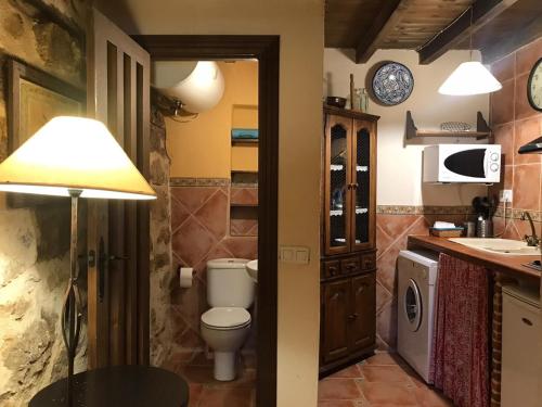 a bathroom with a toilet and a sink and a lamp at La Plazuela - Navalguijo in Navalguijo