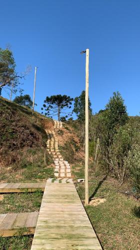 a wooden path on a hill with a pole at Chalé Alto do Morro 2 - conforto e vista deslumbrante in Rancho Queimado