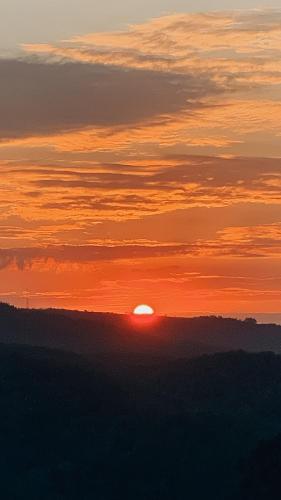 a sunset with the sun setting in the horizon at Chalé Alto do Morro 2 - conforto e vista deslumbrante in Rancho Queimado