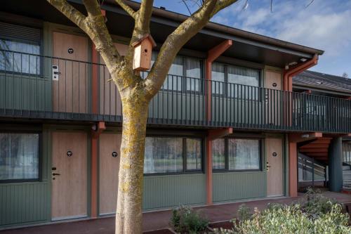 a building with a tree in front of it at Campanile NATURE - Bordeaux Lac in Bordeaux