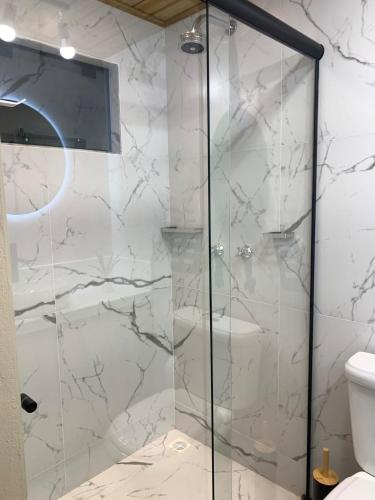 a bathroom with a glass shower with a toilet at Chalé Alto do Morro 2 - conforto e vista deslumbrante in Rancho Queimado